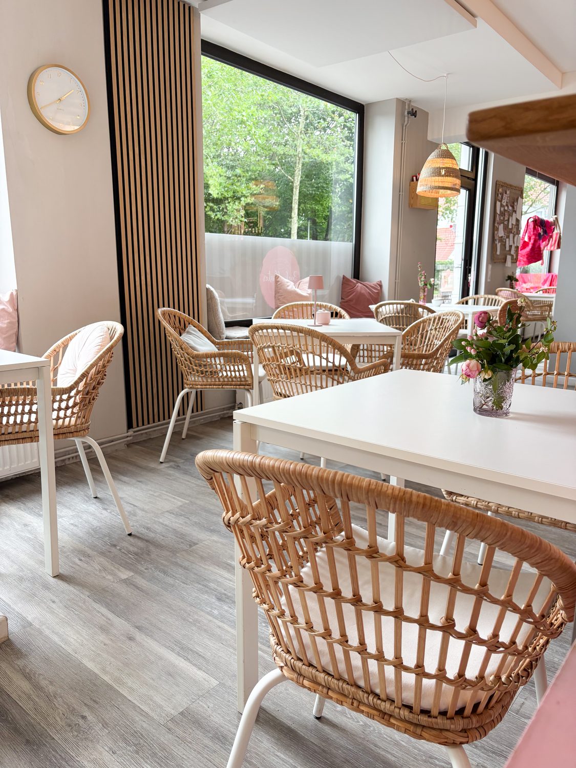 Heller Sitzbereich im Café Backgeflüster mit Rattanstühlen, weißen Tischen und großen Fenstern