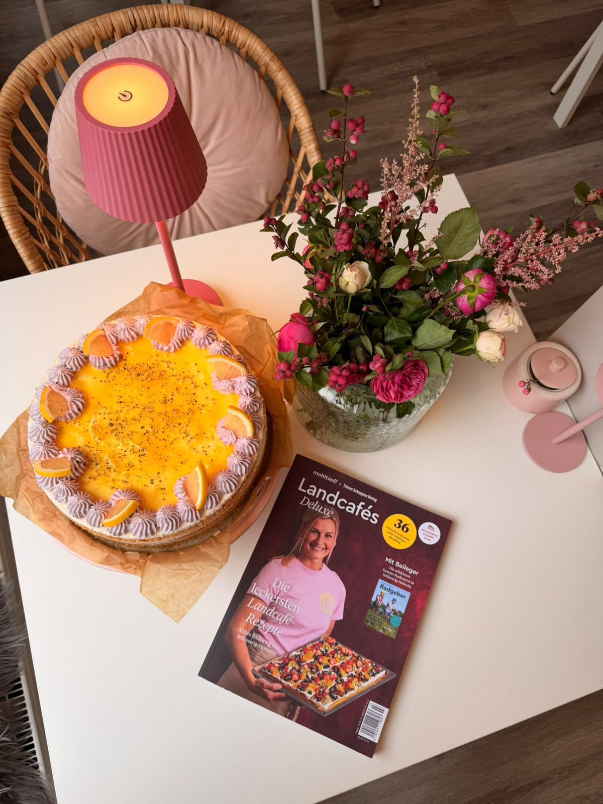 Landcafés Deluxe neben einer Torte und einem Blumenstrauß auf einem Tisch bei Backgeflüster