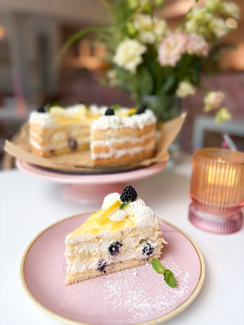 Zitronentorte mit Heidelbeeren auf einem rosa Kuchenständer
